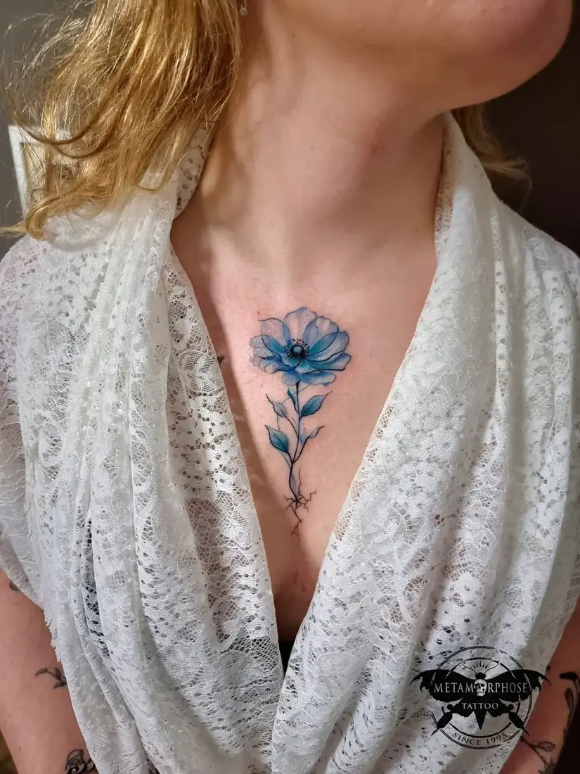Tatouage fleur bleue aquarelle sur le sternum par Mich