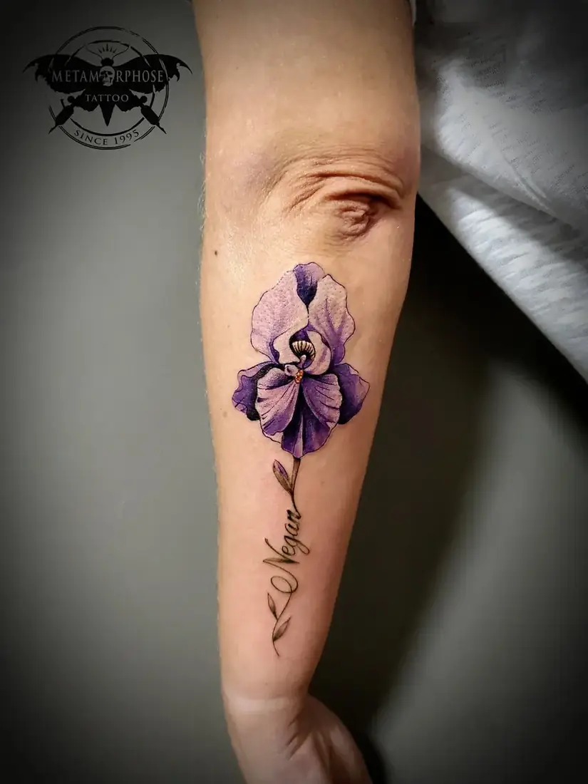 Tatouage iris violet et prénom sur l'avant-bras par Mich