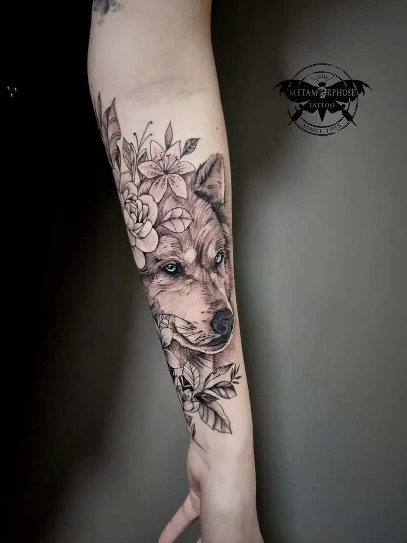 Tatouage loup aux yeux bleus et fleurs sur l'avant-bras par Mich