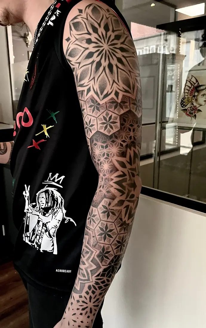 Tatouage mandala et motifs géométriques sur bras entier par Flo