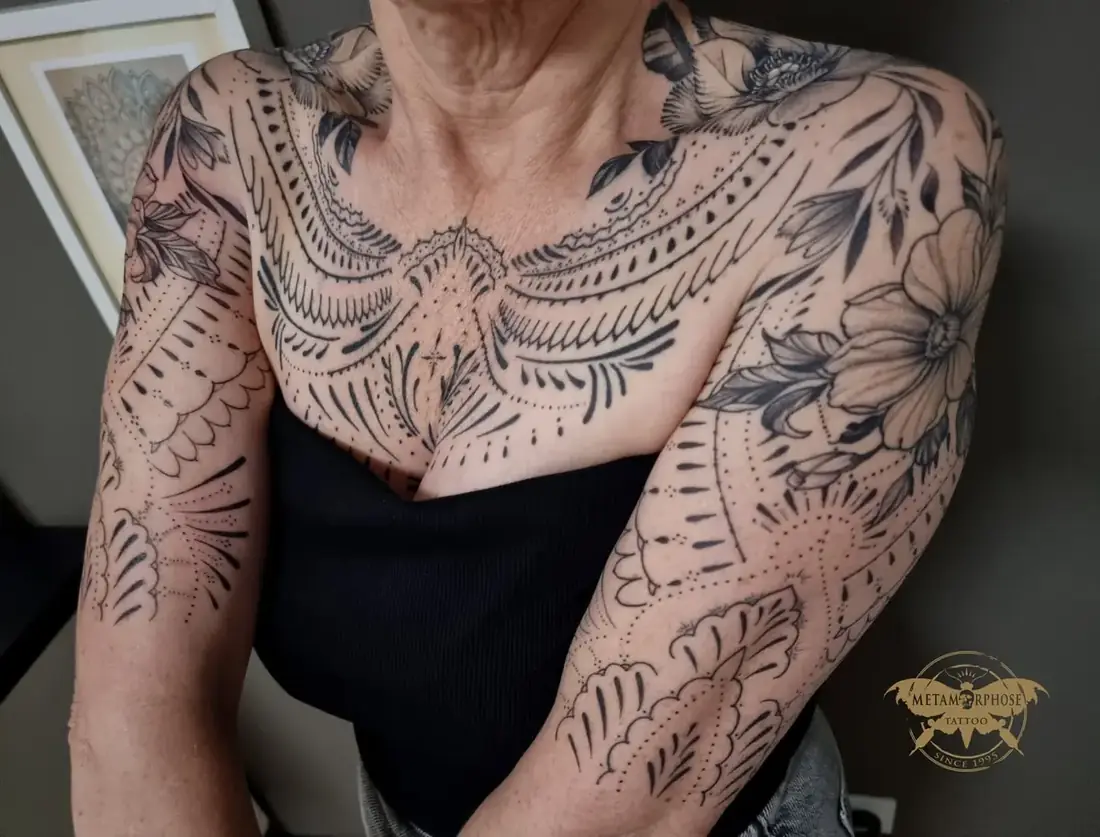 Tatouage ornemental fine line et fleurs sur la poitrine et les bras par Mich