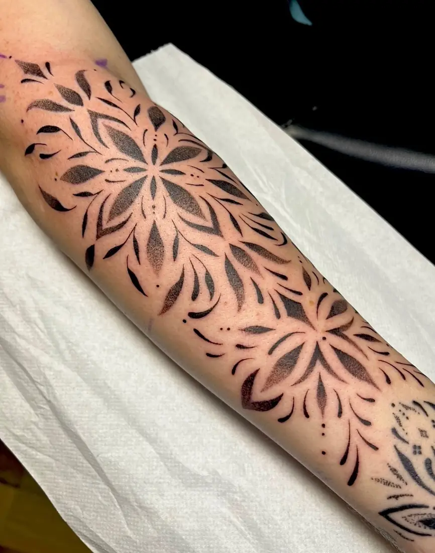 Tatouage ornemental floral en manchette sur l'avant-bras par Flo
