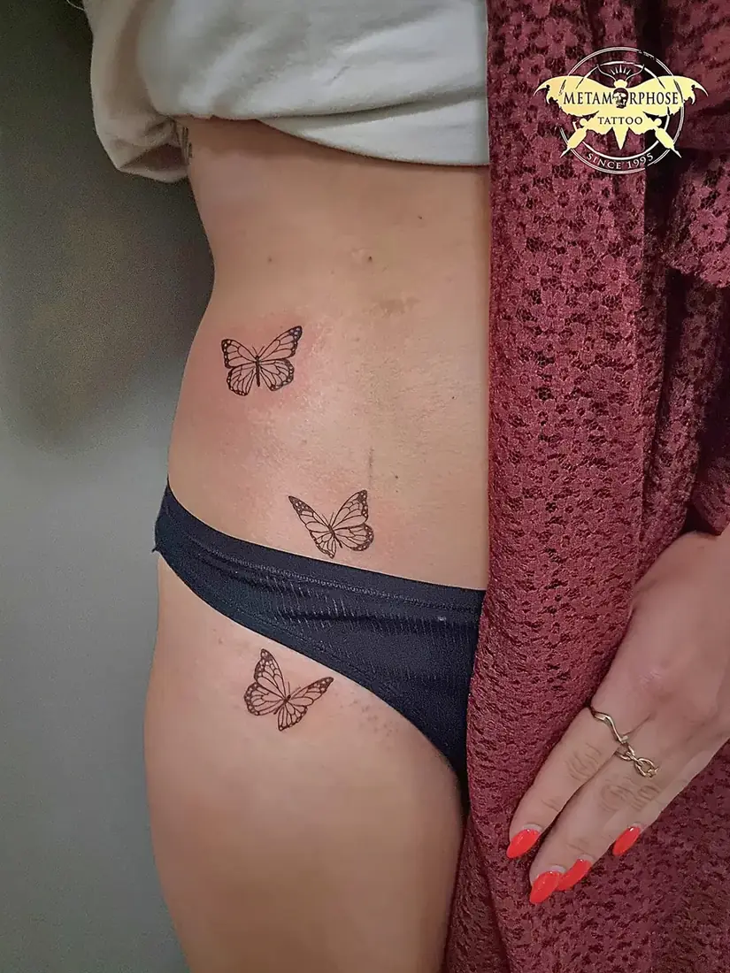 Tatouages trois papillons fine line sur la hanche par Mich